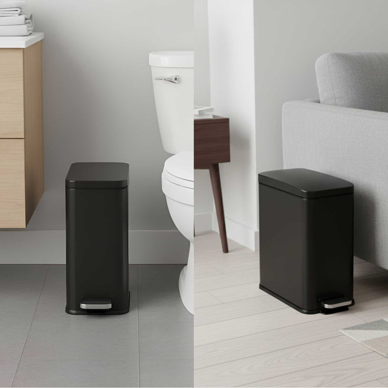 iTouchless black step trash can in a bathroom setting with a toilet in the background and living room between couch and wall.