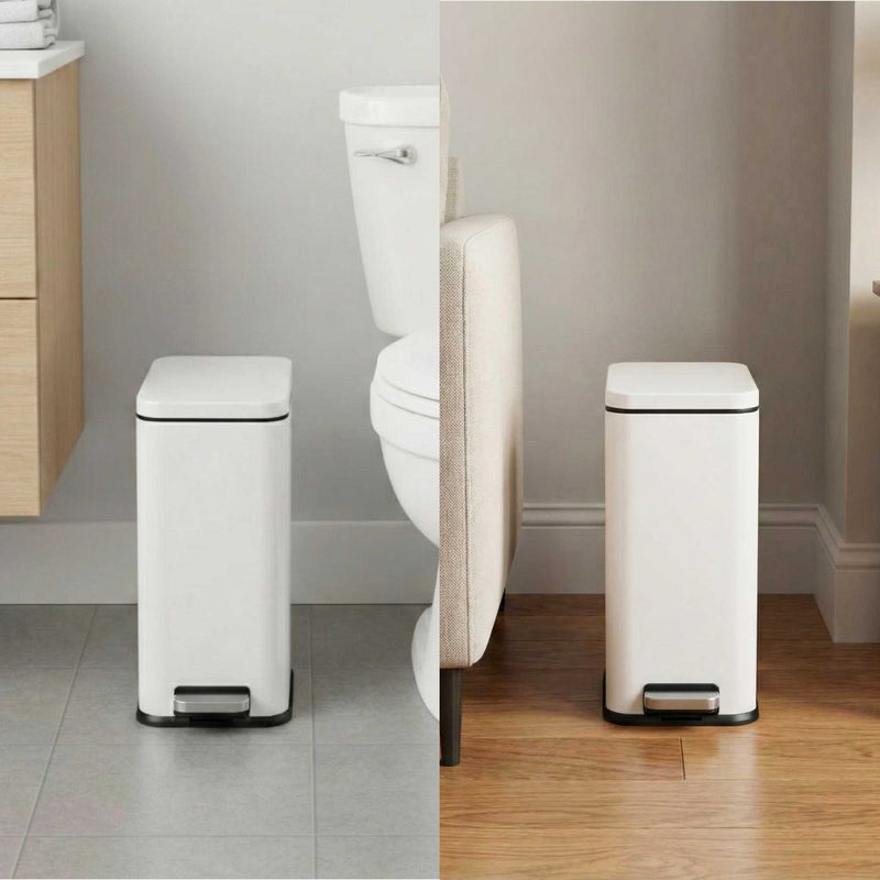 iTouchless white step trash can in a bathroom setting with a toilet in the background and living room between couch and wall.