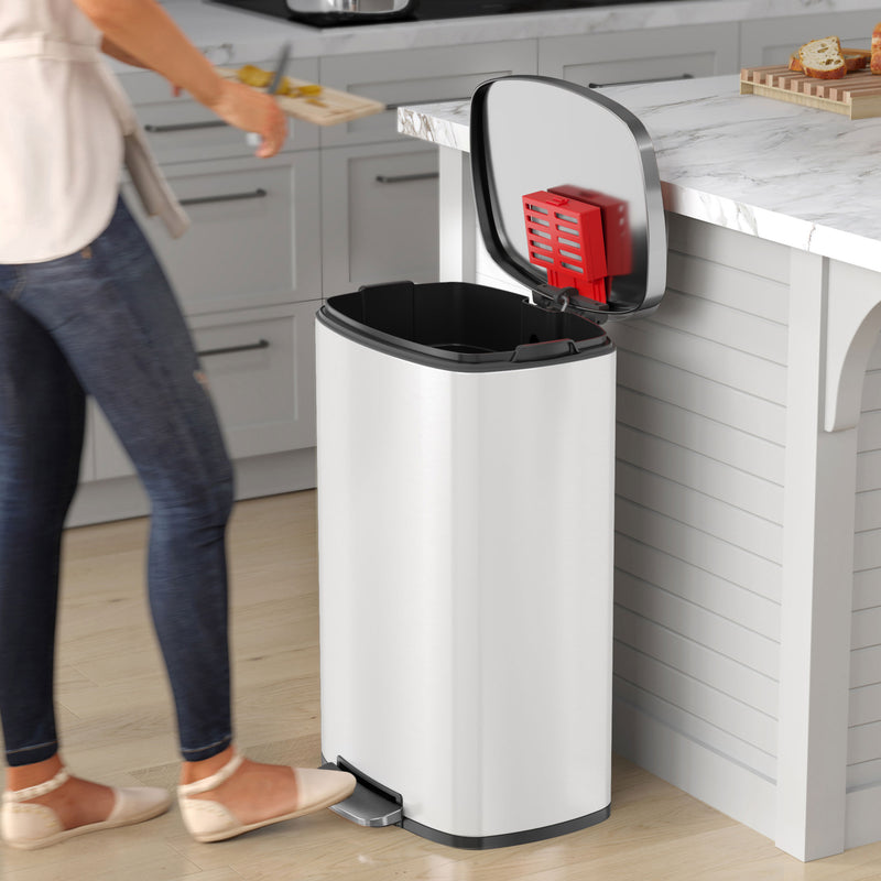 Woman using ivory white step trash can in modern kitchen, showing hands-free pedal and soft-closing lid.